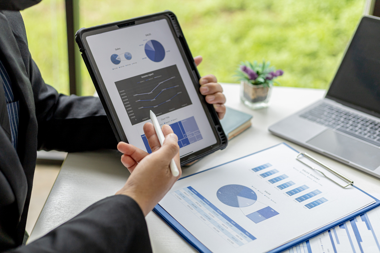 Businessman holding a tablet showing sales data of a salesperson, he is meeting with the sales manager to plan sales growth management, marketing plan to increase sales. Sales management concept.